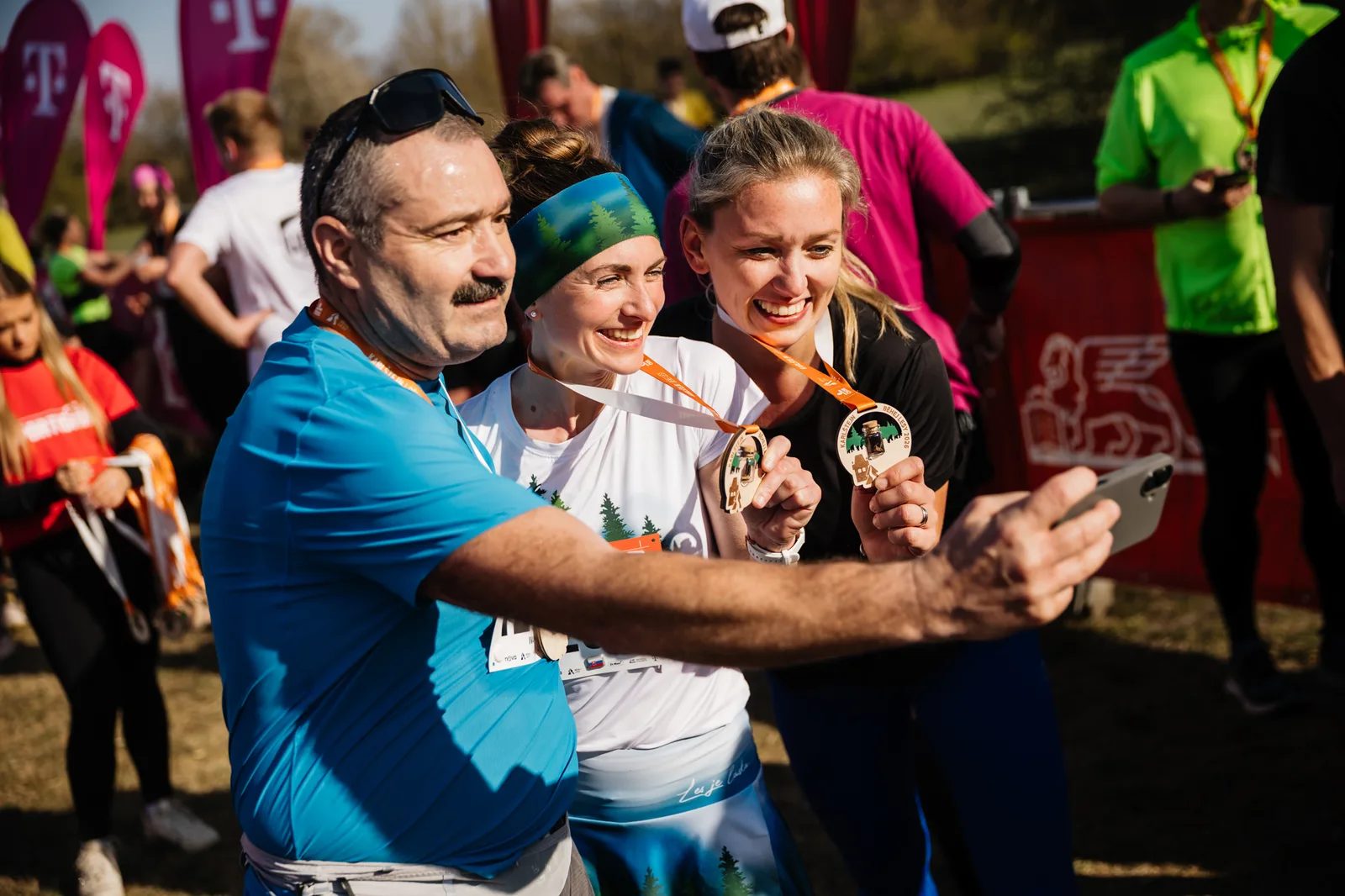 Závodníci s medailemi si dělají selfie v cíli