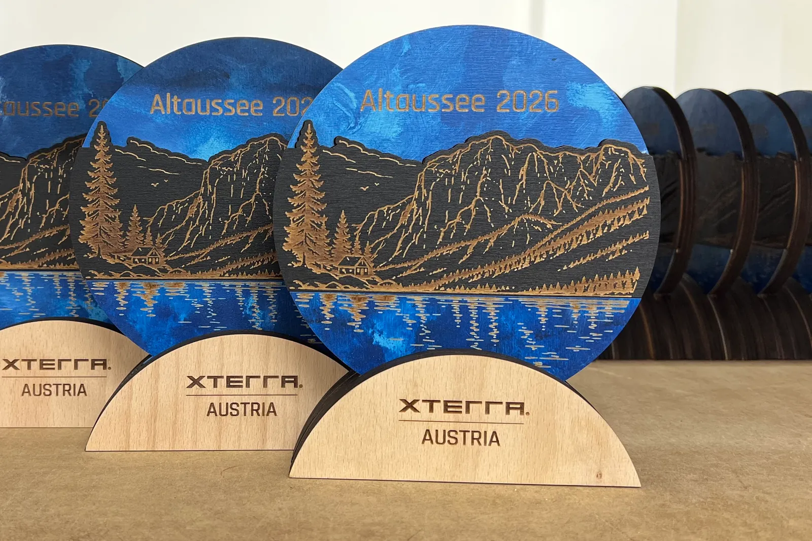 Vícevrstvé trofeje XTERRA Austria s modrým jezerem a horami Altaussee v dílně